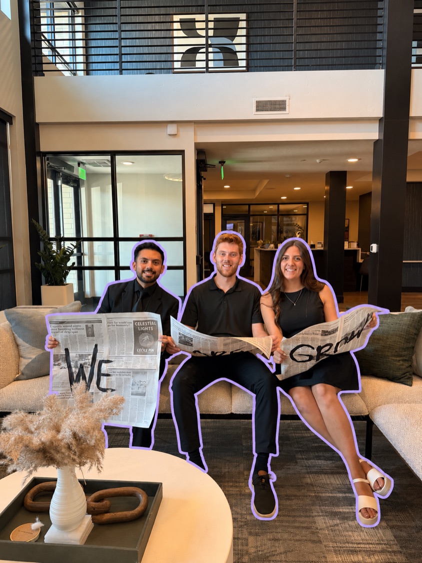 The Grow Studio founders laughing behind newspapers